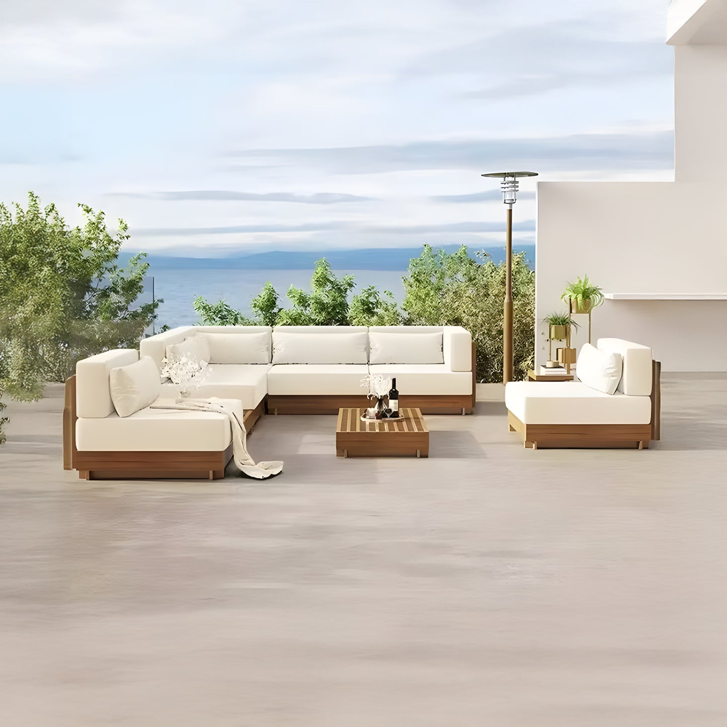 The outdoor patio features Landmark Decors Santorini Serenity Collection: modern wooden and white cushioned L-shaped seating with all-weather frames around a low table, accompanied by a standalone heater. Green trees and a clear sky provide a peaceful backdrop.