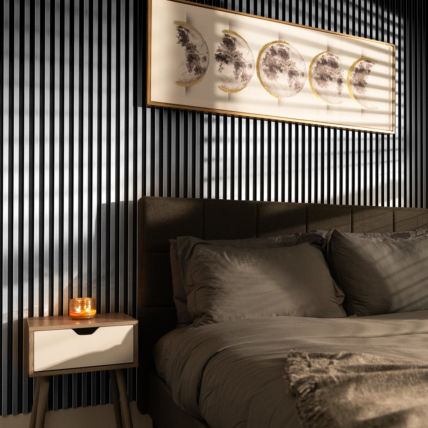 A neatly made bed with gray bedding sits next to a nightstand with a lit candle; above them, framed lunar phase art hangs on Landmark Decor’s Bright Silver WPC Fluted Slat Wall Panel.