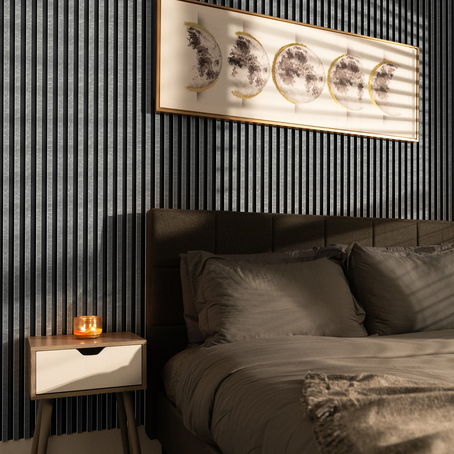A neatly made bed with grey bedding sits next to a small nightstand and lit candle, set against Landmark Decor’s Urban Mist Mosaic WPC Fluted Slat Wall Panel, with a moon phase artwork displayed above.