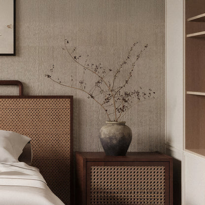 A ceramic vase with dried branches sits on a wooden nightstand beside a bed with a rattan headboard, while Landmark Decor’s Cut Stone Sheet - Beige lends subtle texture to this neutral-toned bedroom.