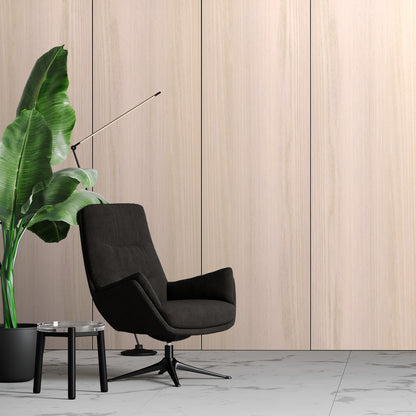 A modern black swivel chair sits by a glass-top side table and large potted plant, set against Landmark Decor’s Bleached Oak Carbon Sheet wall panels on a marble floor.