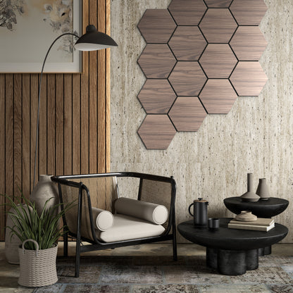 A modern living room featuring a cane armchair, black coffee table, Landmark Decor White Oak Hexagon Wood Wall Panels, potted plant, and neutral-toned decor.