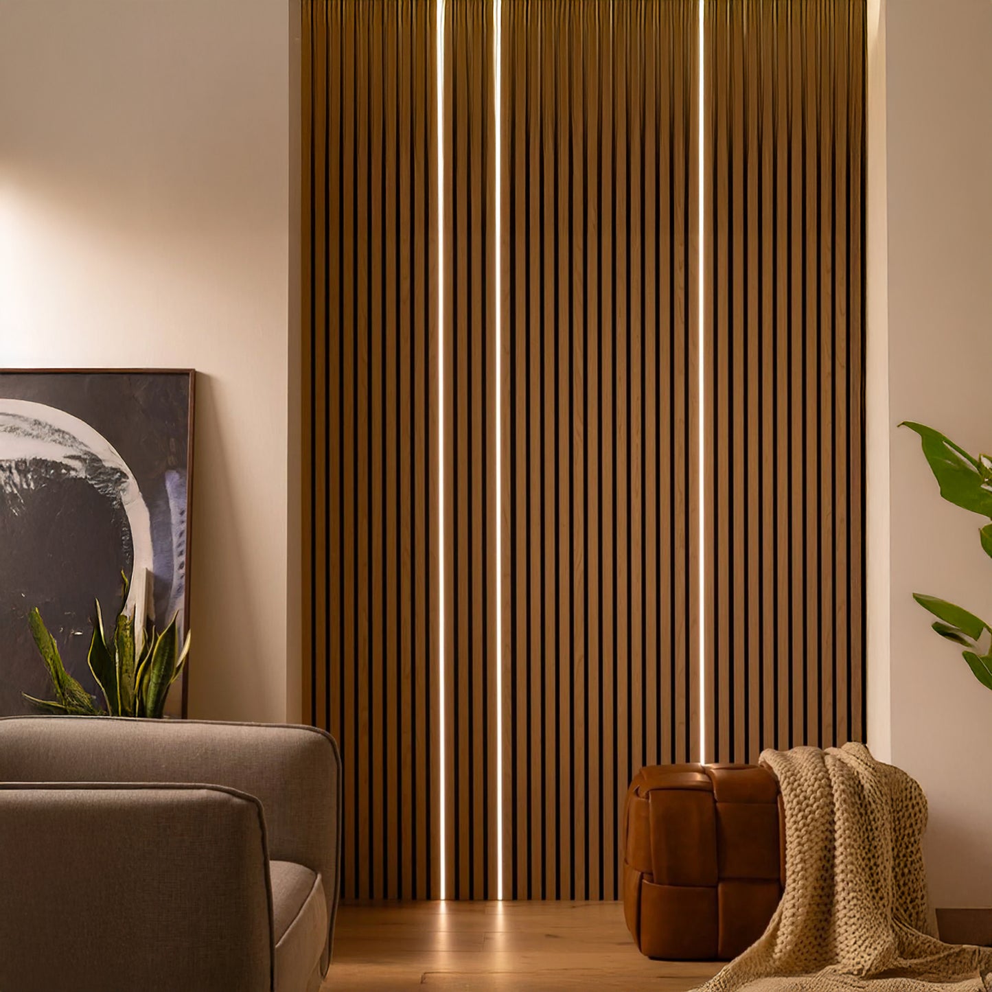 A modern living room featuring Landmark Decor LED Lights, vertical wooden slats, a gray sofa, a brown leather ottoman with a beige blanket, plants, and a framed abstract painting on the floor.