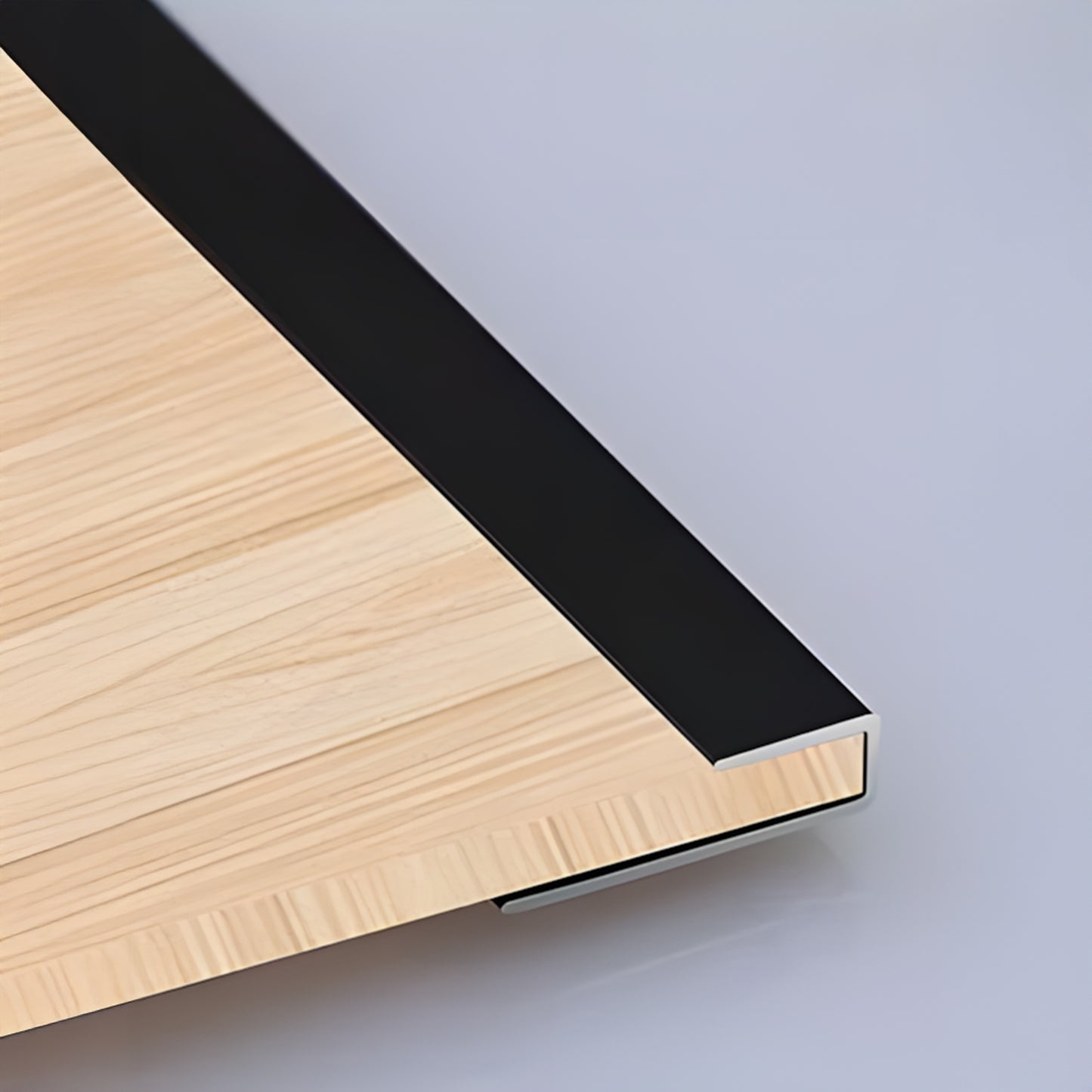 Close-up of the PVC Wall L Shape Strip by Landmark Decor: light wood panel corner with black metal trim, highlighting panel edges and wall accessories against a smooth, light-colored background.