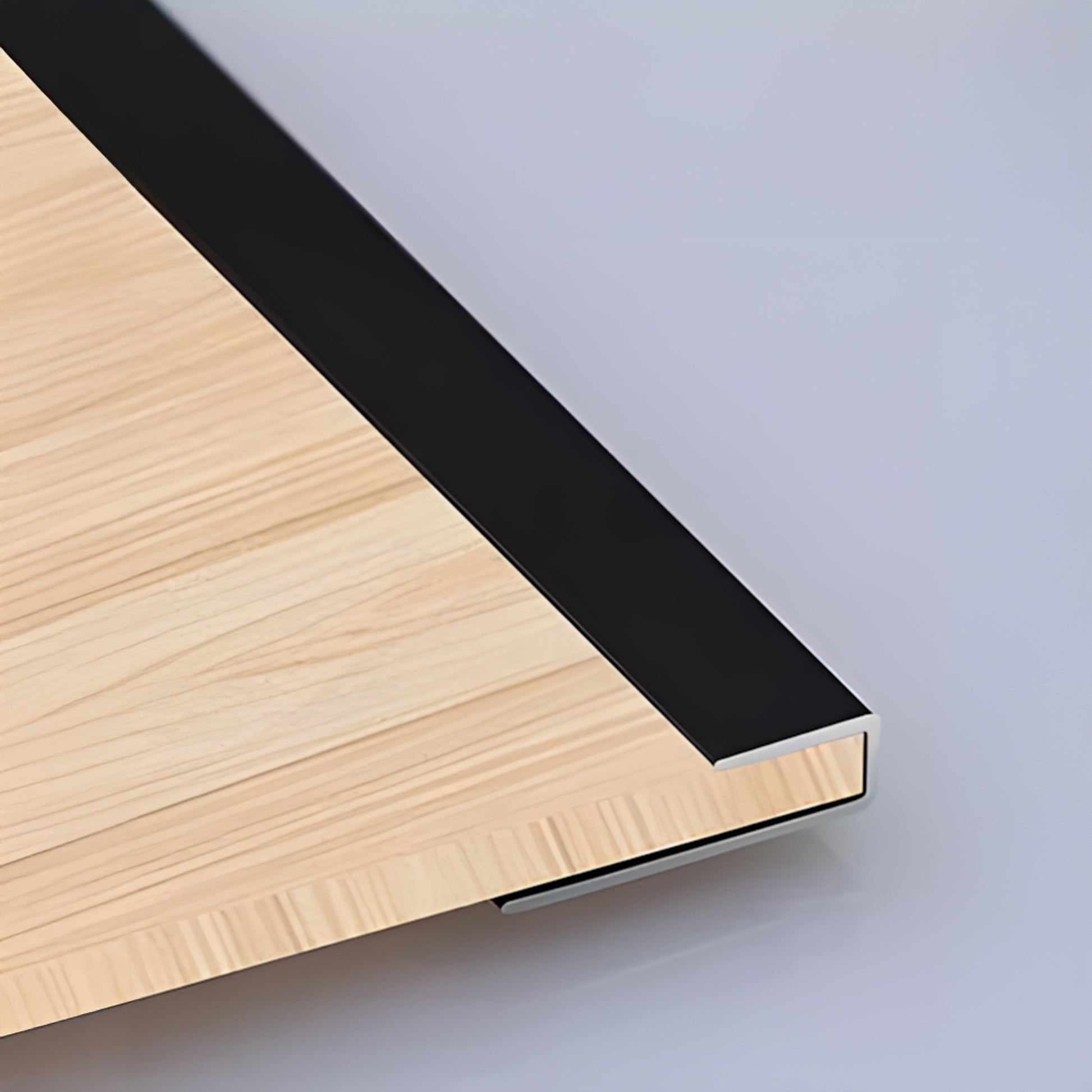 Close-up of the PVC Wall L Shape Strip by Landmark Decor: light wood panel corner with black metal trim, highlighting panel edges and wall accessories against a smooth, light-colored background.