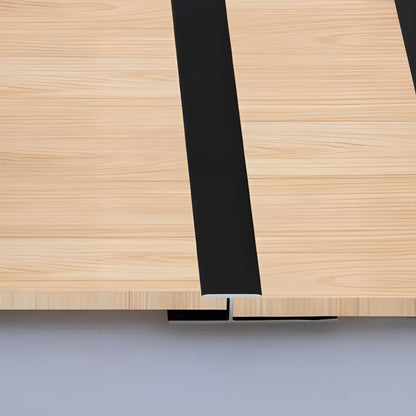 Close-up of a light wood table featuring two wide black PVC Wall Middle Strips by Landmark Decor, running lengthwise and resembling panel edges often seen in wall panel installations.