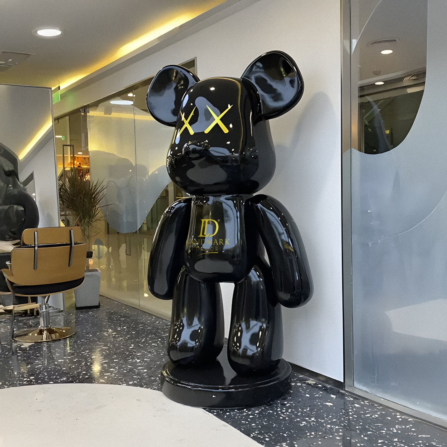 The Black Bear - Large by Landmark Decor features a glossy black finish, yellow X eyes, and a D logo—an artistic sculpture that makes a bold statement in modern rooms or as unique home decor.