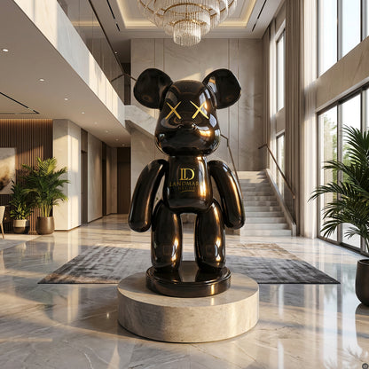 The Black Bear - Large by Landmark Decor is a glossy black bear statue with gold accents, displayed on a pedestal in a modern, marble-floored lobby with tall windows and potted plants—an artistic statement piece.