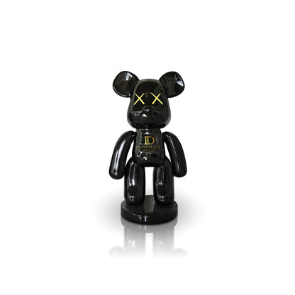 The Black Bear - Medium by Landmark Decor is a glossy black bear-shaped figurine with yellow X eyes and "LANDMARK" on its chest, perfect for adding a bold accent to your space or Landmark Decor collection. Displayed against a white background.