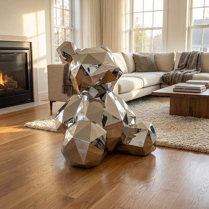The Polish Sitting Bear by Landmark Decor—a faceted, reflective metallic sculpture—sits on a wooden floor in a modern living room with a beige sofa, shag rug, and fireplace.