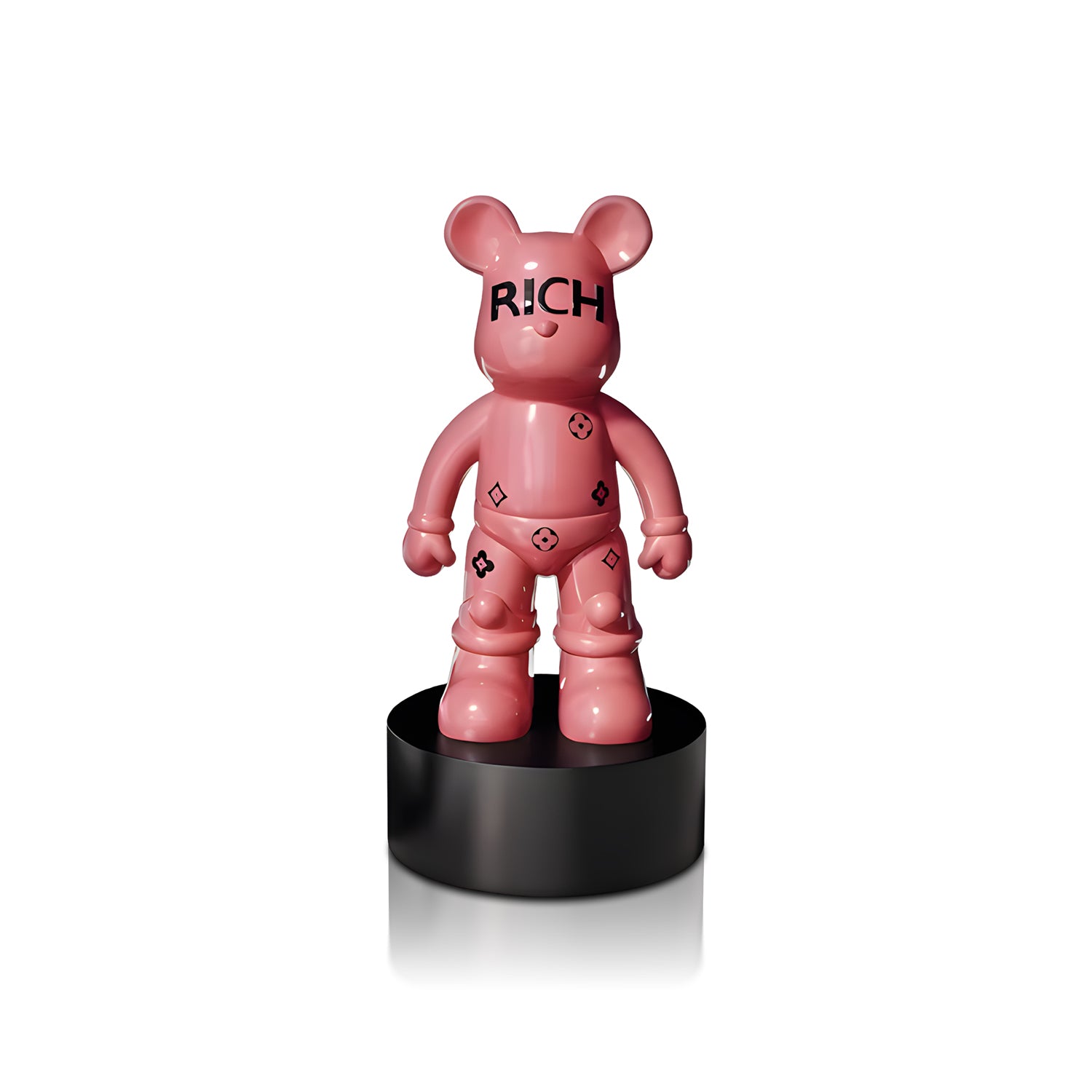 The Rich Bear by Landmark Decor is a pink bear-shaped figurine on a black round pedestal, featuring "RICH" on its face and black symbols—an eye-catching accent for modern interiors and unique home decor.