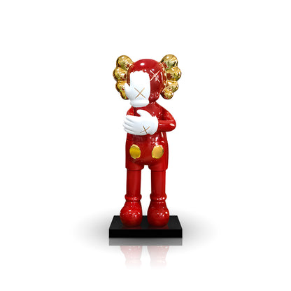 The Landmark Decor SMH features a red cartoon-style figure with gold ears and white crossed-out eyes on a black base, holding a white object—a unique sculpture ideal for home decor or as an artistic accent piece.