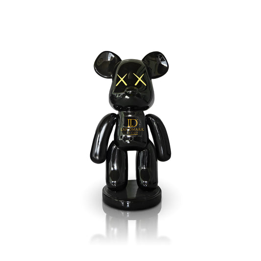 The Black Bear - Large by Landmark Decor is a glossy black bear figurine with yellow X eyes and "LANDMARK" on its chest, standing on a round base—ideal as bold interior decor against a white backdrop.