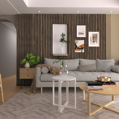 A modern living room featuring a gray sofa, light wood accents, Walnut Texture WPC Fluted Slat Wall Panel by Landmark Decor as an accent wall, decorative plants, and two round coffee tables on a textured rug.