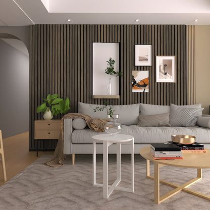 Modern living room featuring a gray sofa, decorative pillows, round tables, potted plants, and framed art displayed on Landmark Decor Cassia Wood Texture WPC Fluted Slat Wall Panels for a stylish accent backdrop.