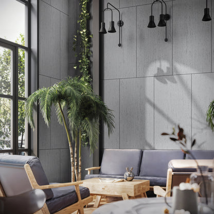 Modern living room with gray walls, a black sofa, light wood furniture, potted palm, vertical greenery, large windows, and black wall-mounted lights highlighted by Landmark Decor's Travertine Stone Sheet in white.