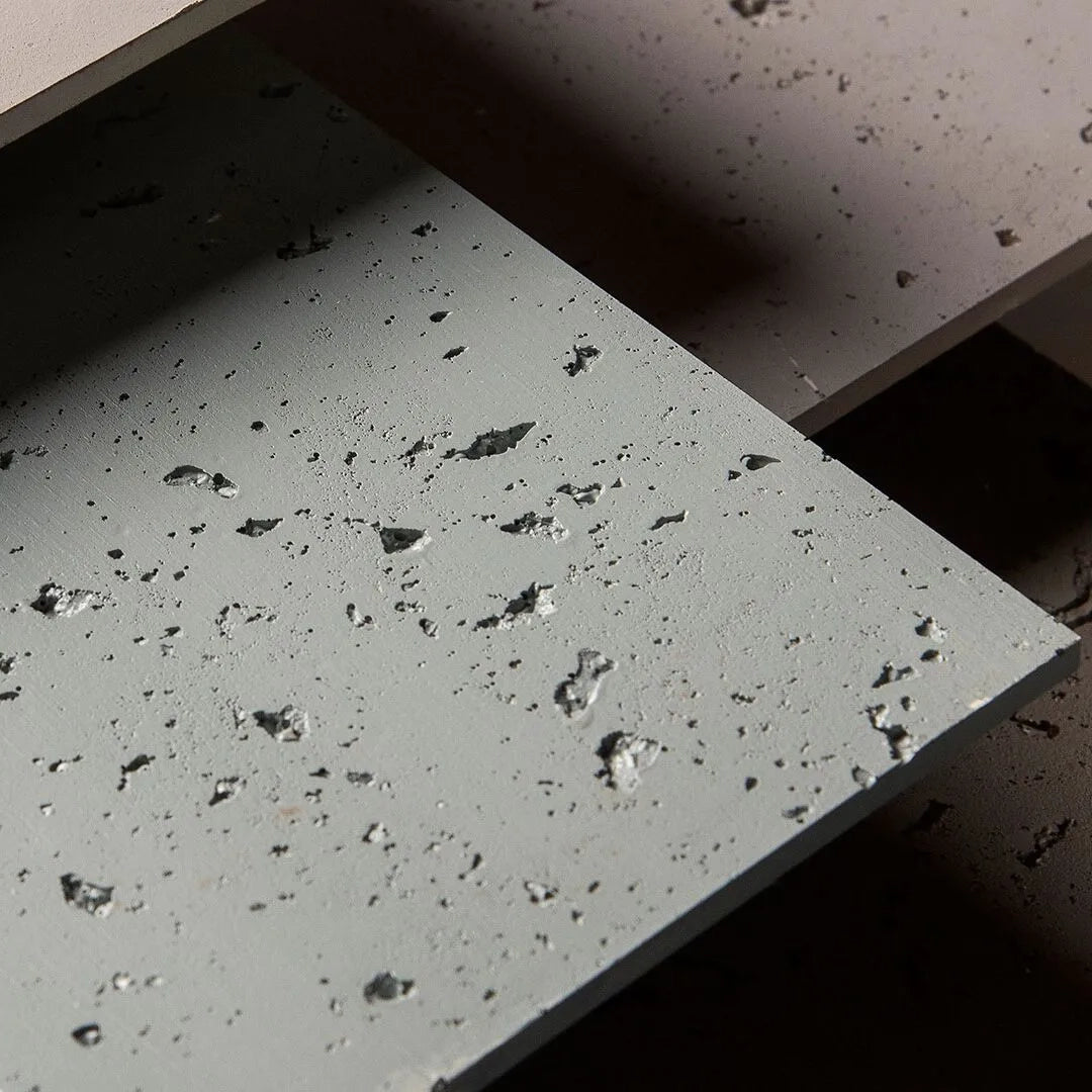 Close-up of Landmark Decor’s Travertine Stone Sheet - White: concrete-like slabs with visible holes and rough texture, stacked in layers under direct light, mimicking the natural stone finish of flexible sheets.