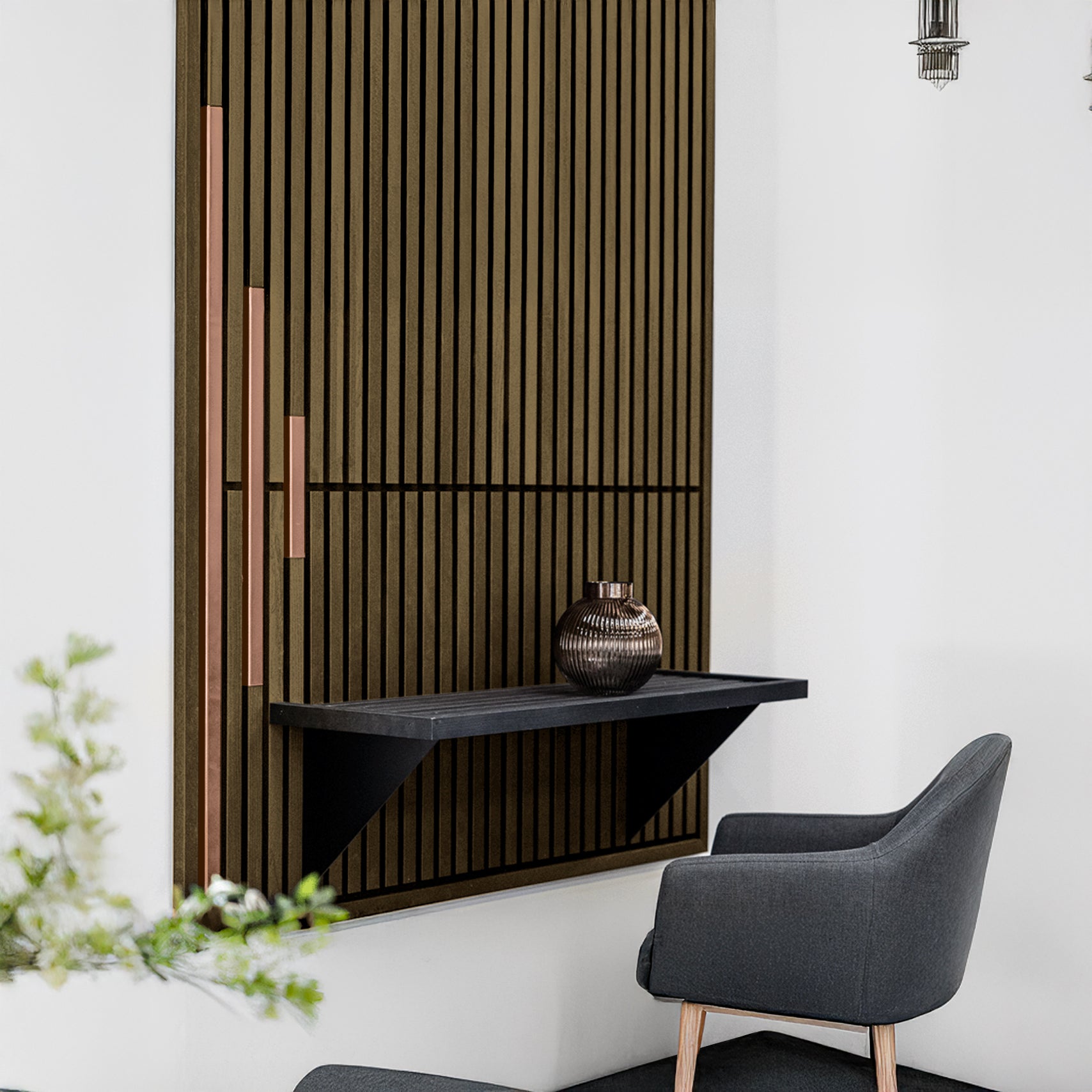 A modern corner features a gray armchair, a black floating shelf with a decorative vase, and Landmark Decor's Wood Panel Metal Cover-Rose Gold for added style.